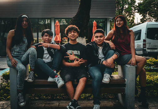 A group of people sitting on top of a wooden bench