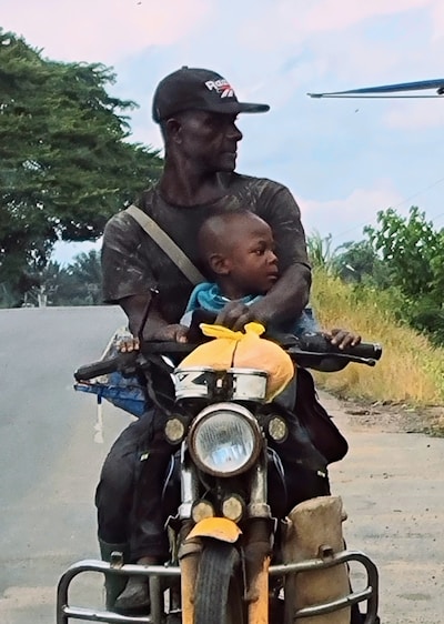 A man riding a motorcycle with a child on the back of it