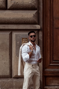 A man in a white shirt and tan pants standing in front of a door