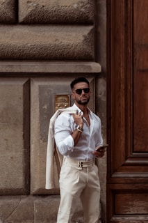 A man in a white shirt and tan pants standing in front of a door