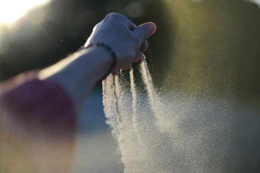 A person holding their hand out to spray water