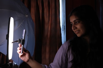 A woman holding a cell phone in front of a light