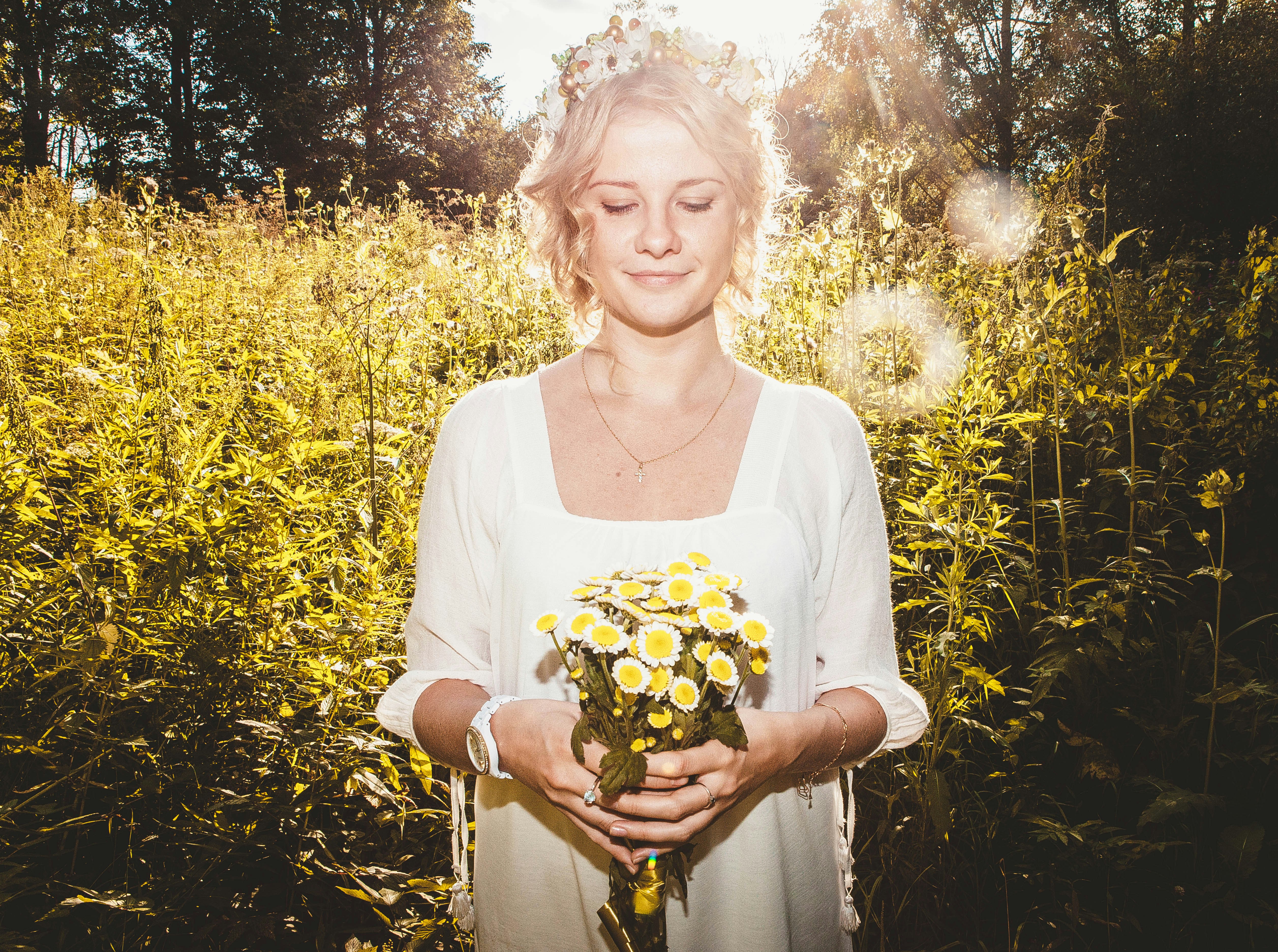 A woman standing in a field holding a bouquet of flowers