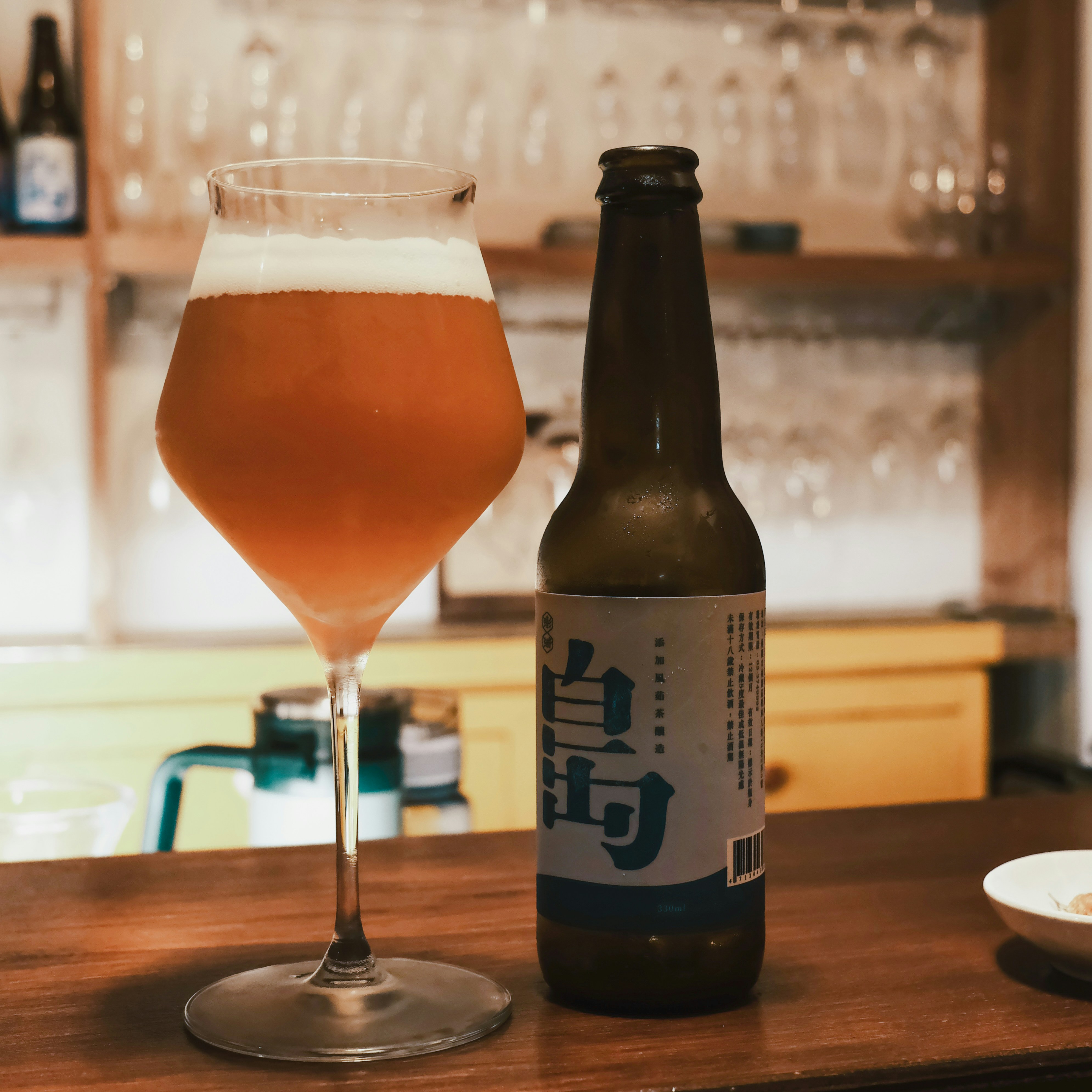 A glass of beer sitting next to a bottle of beer