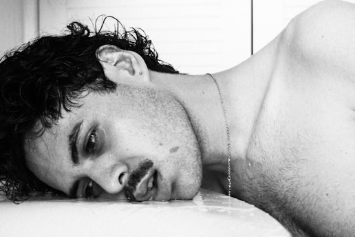 A man laying on top of a bed next to a window