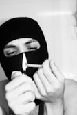 A man in a mask lighting a cigarette