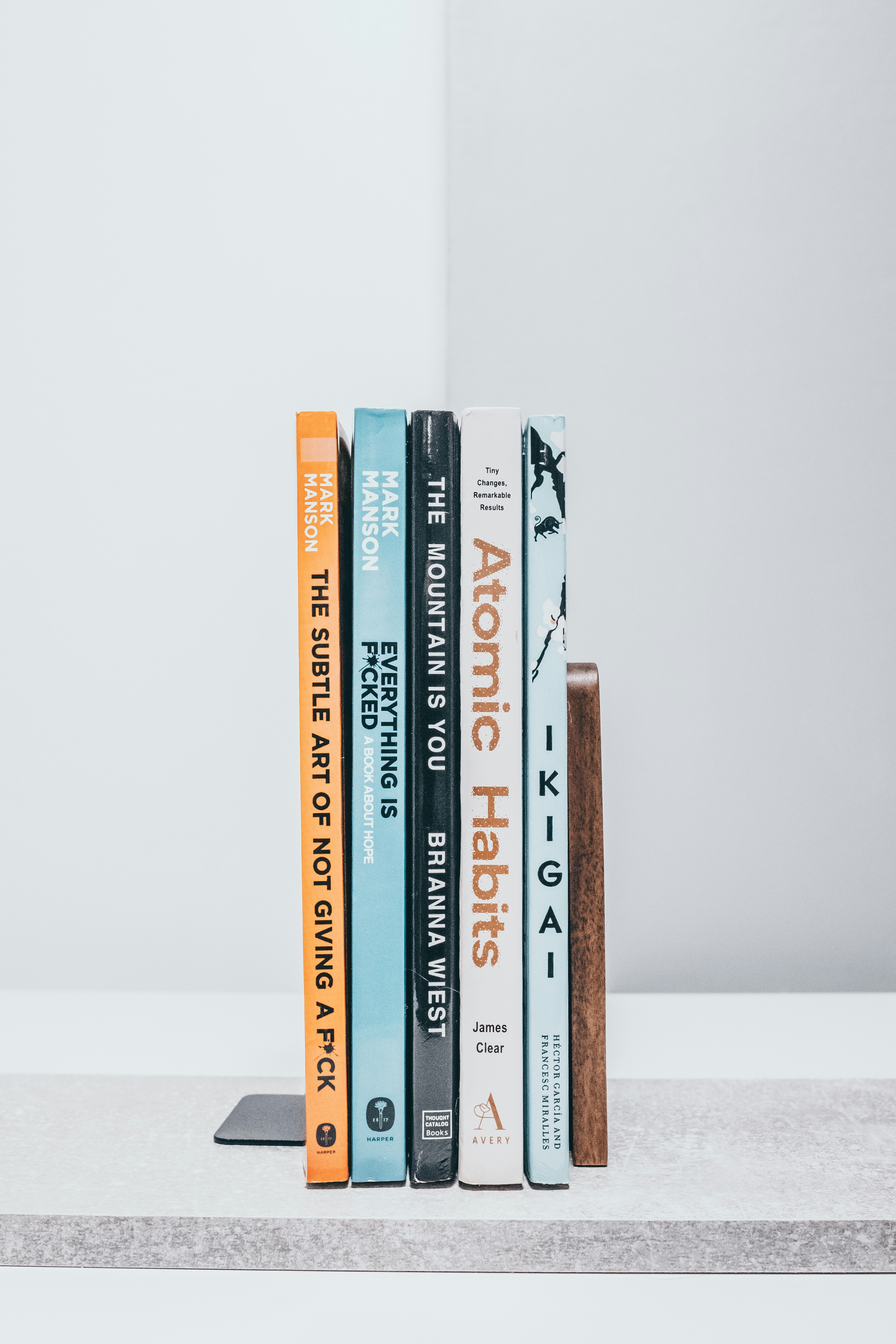 A row of books sitting on top of a white shelf