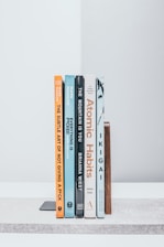 A row of books sitting on top of a white shelf