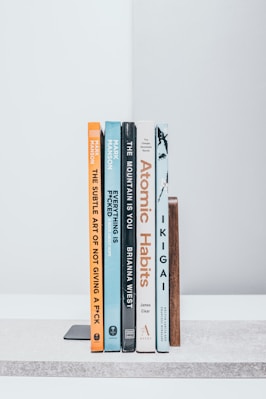 A row of books sitting on top of a white shelf