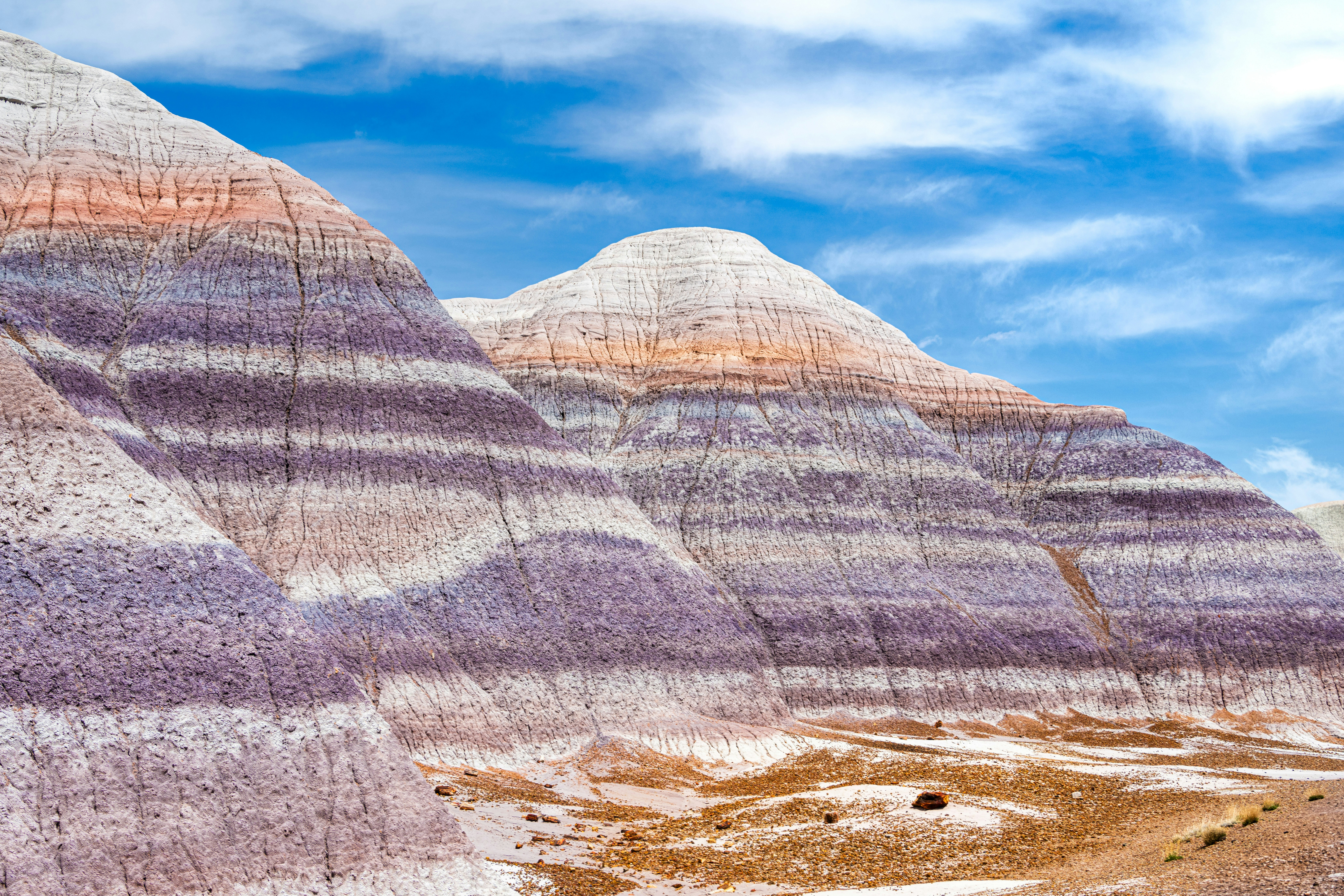 A group of mountains with a blue sky in the background, Vibrant, multi-colored striped hills under a bright blue sky on the Blue Mesa Canyon trail in Petrified Forest National Park
