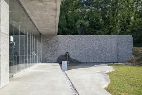 A concrete building with glass doors and a black trash can