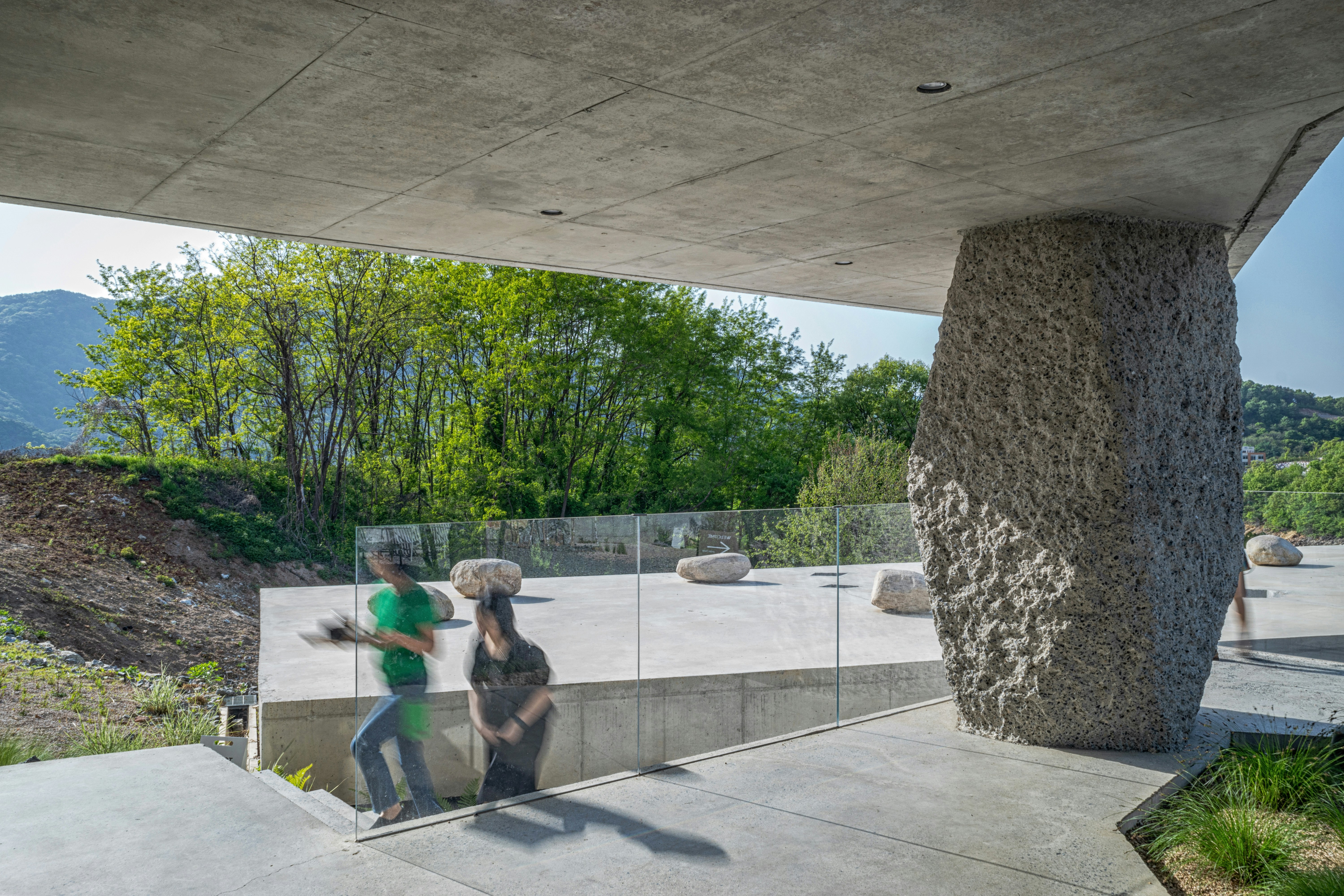 A couple of people sitting on a bench under a bridge