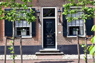 A building with a black door surrounded by trees