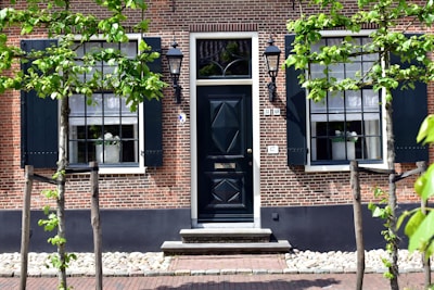 A building with a black door surrounded by trees