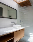 A bathroom with a sink, mirror, and shower