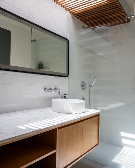 A bathroom with a sink, mirror, and shower