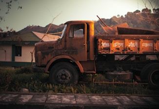 An old rusted truck is parked in a yard