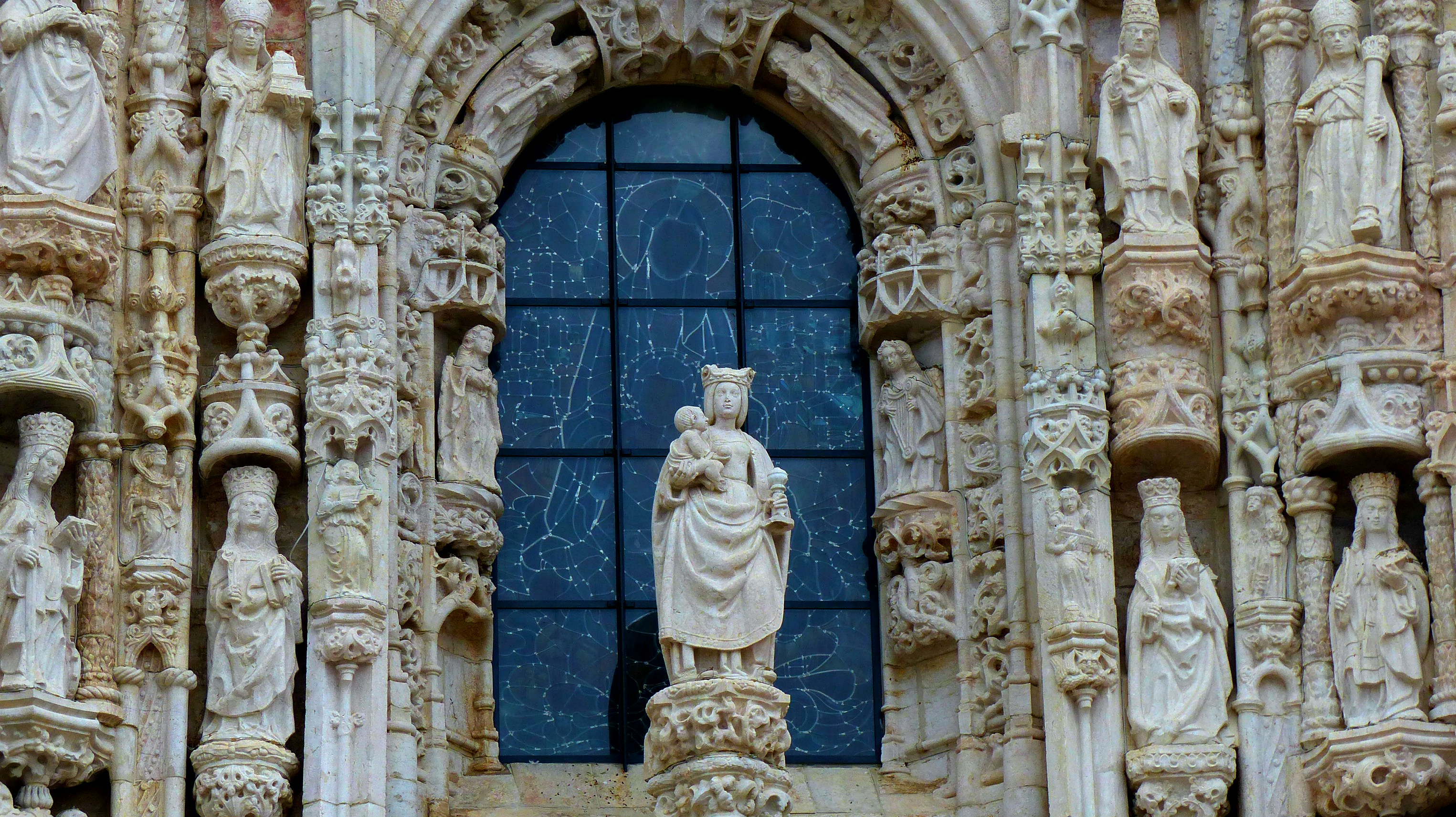 A stone building with a blue window and a statue in front of it