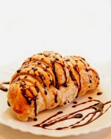 A pastry with chocolate drizzled on top of it