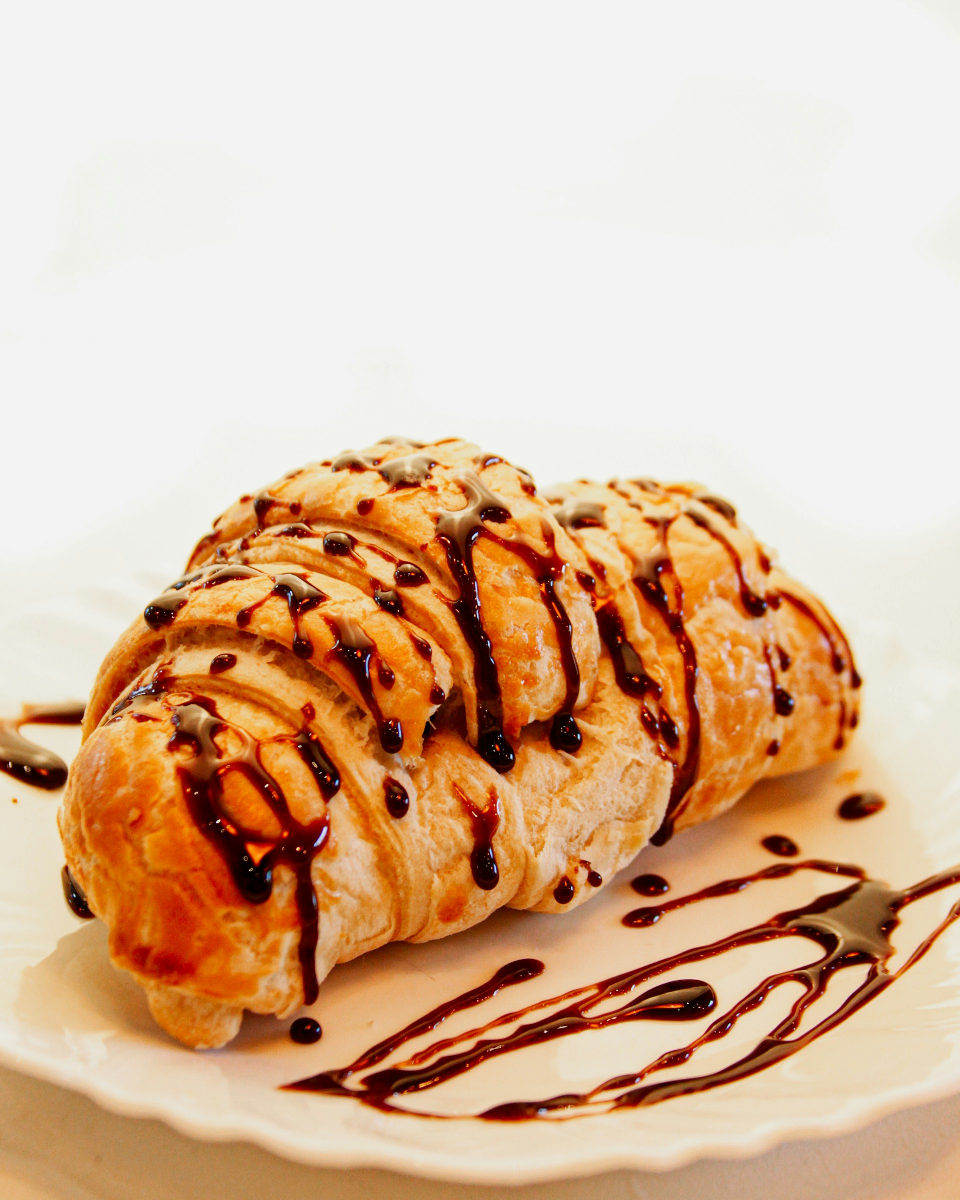A pastry with chocolate drizzled on top of it