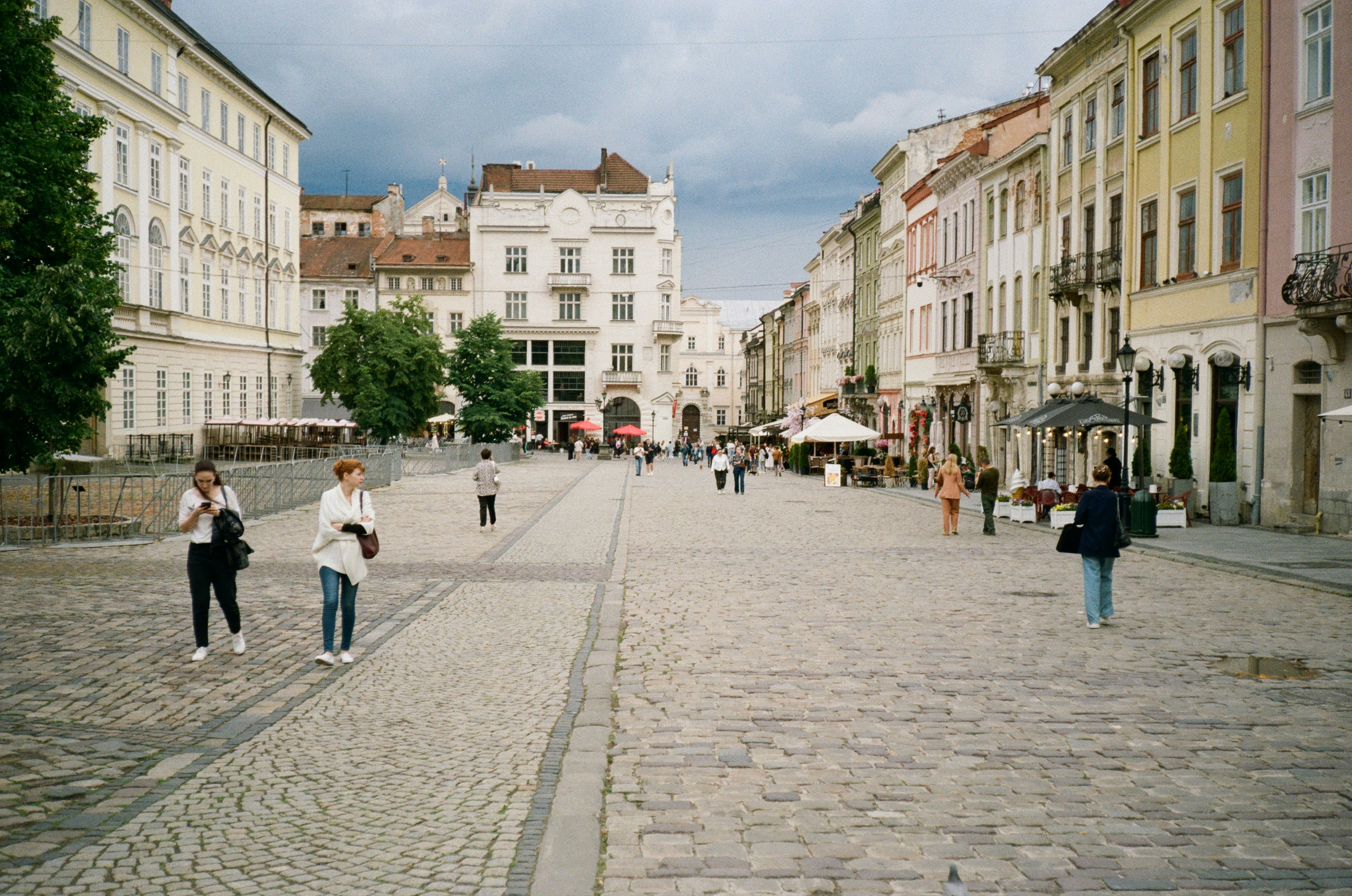 A group of people walking down a street next to tall buildings