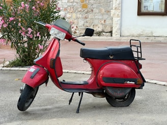 A red scooter parked on the side of the road