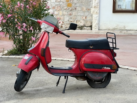 A red scooter parked on the side of the road