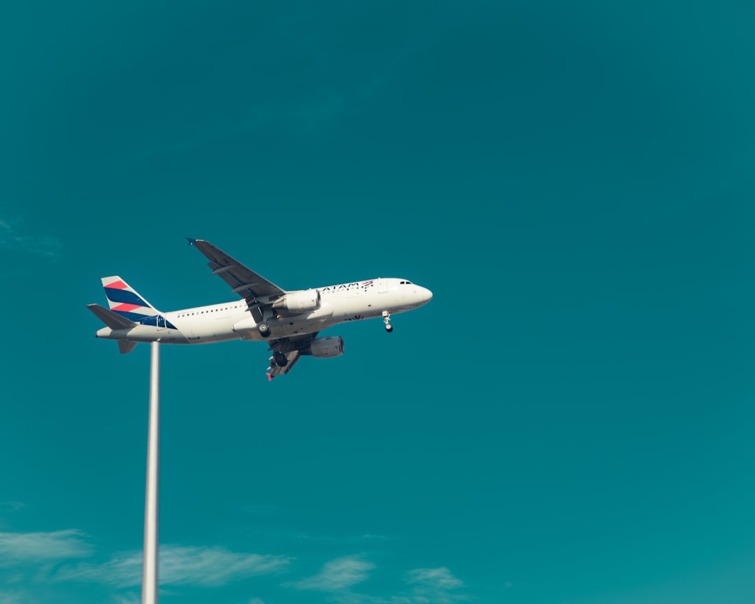 An airplane flying in the sky over a parking lot,