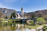A small bridge over a river with a church in the background