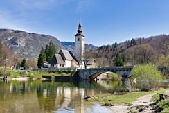 A small bridge over a river with a church in the background