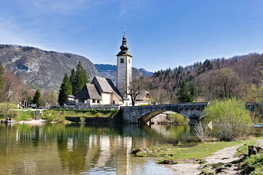 A small bridge over a river with a church in the background