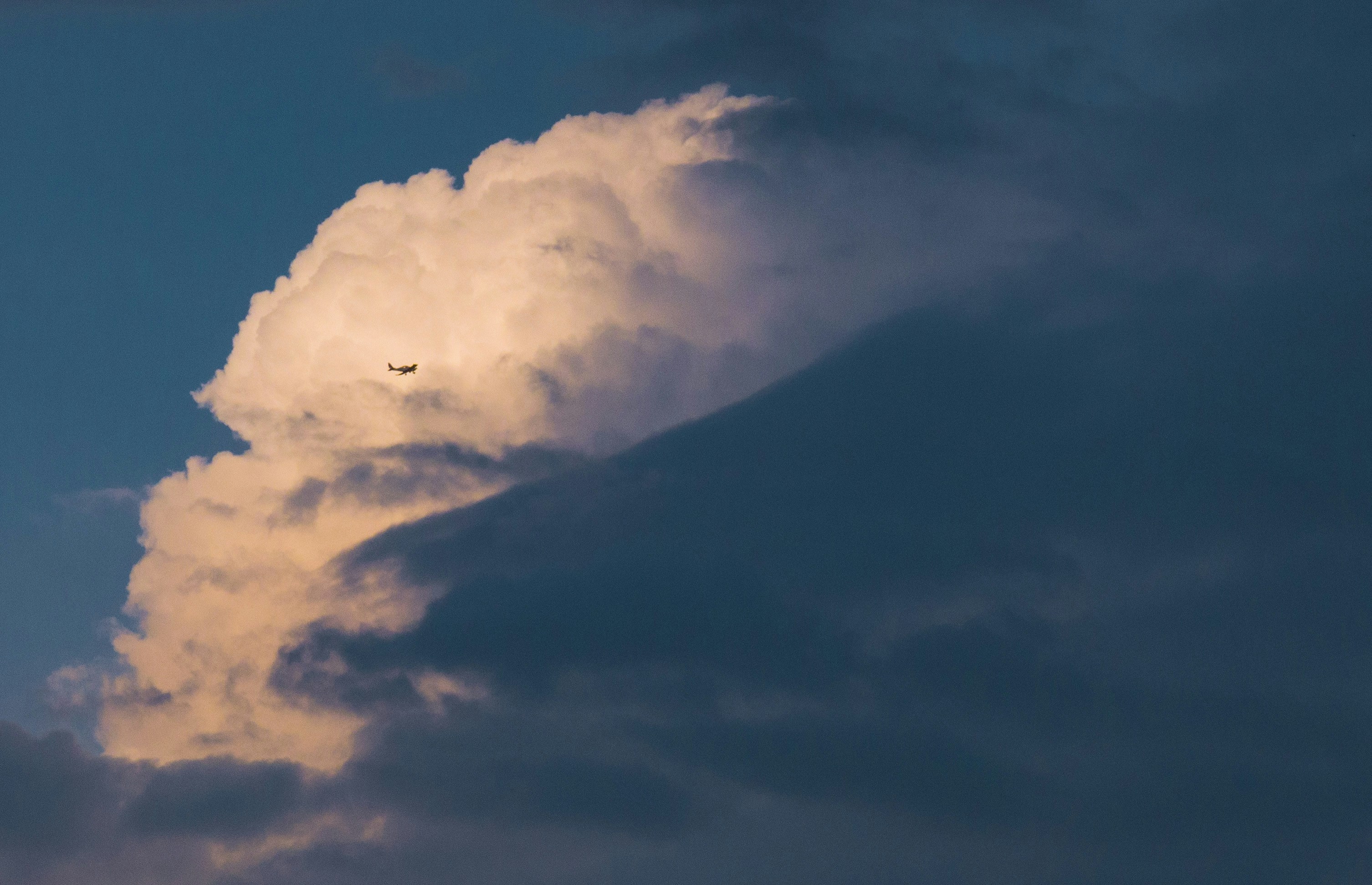 A plane flying through a cloudy sky at sunset
