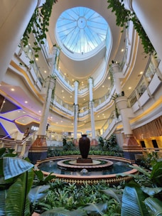 A large atrium with a fountain surrounded by greenery