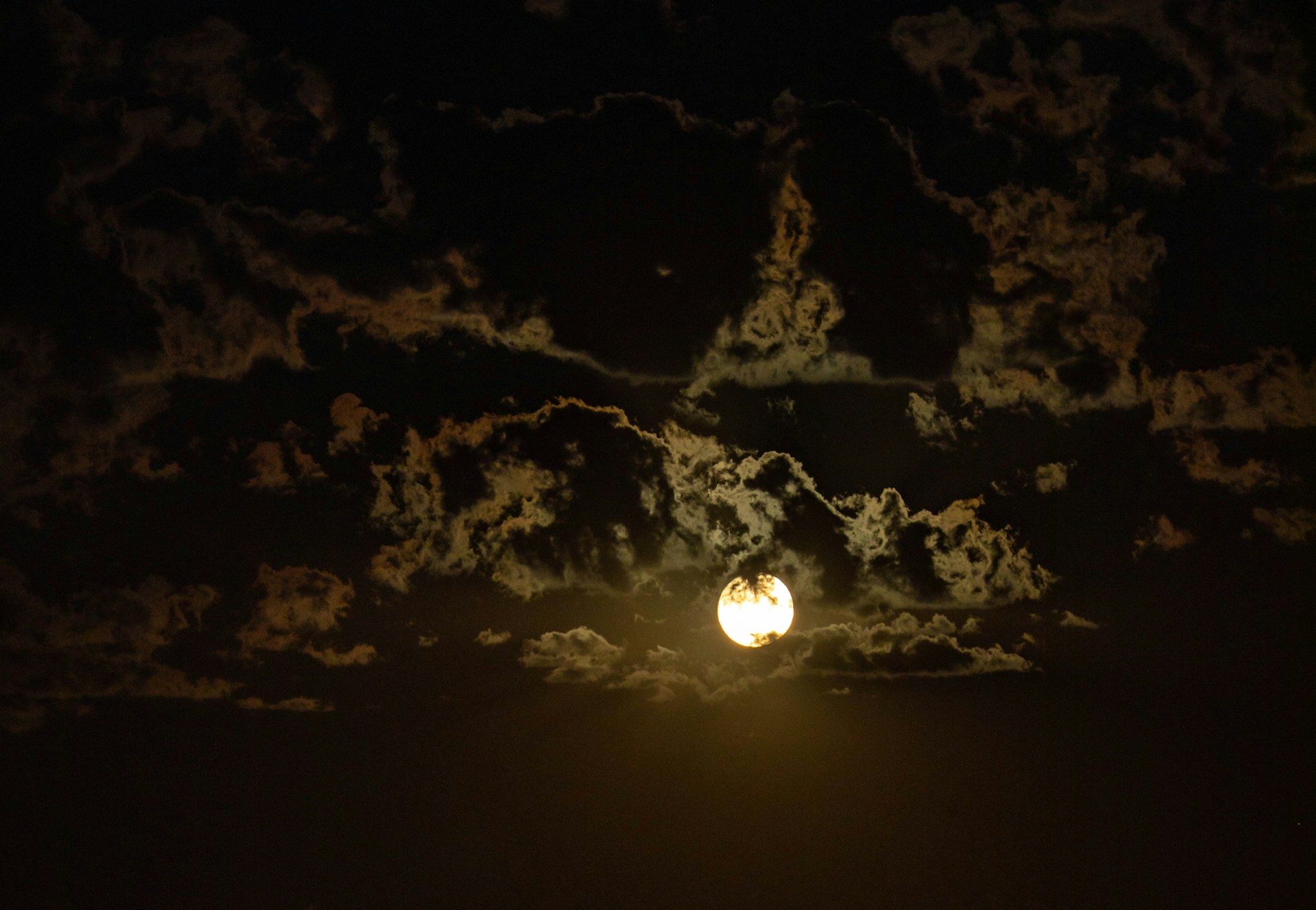 A full moon in the night sky with clouds