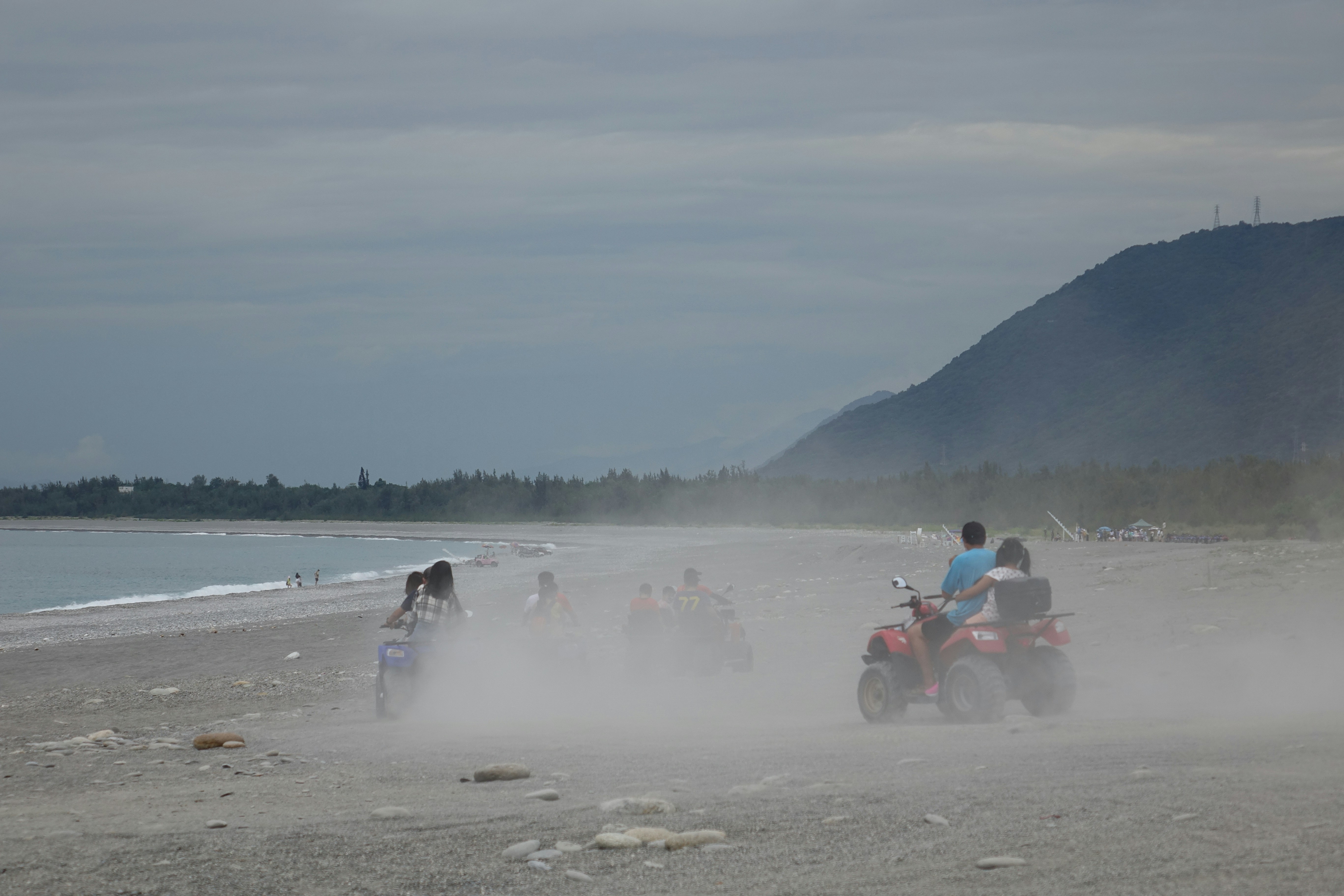 A group of people riding four wheelers on a beach