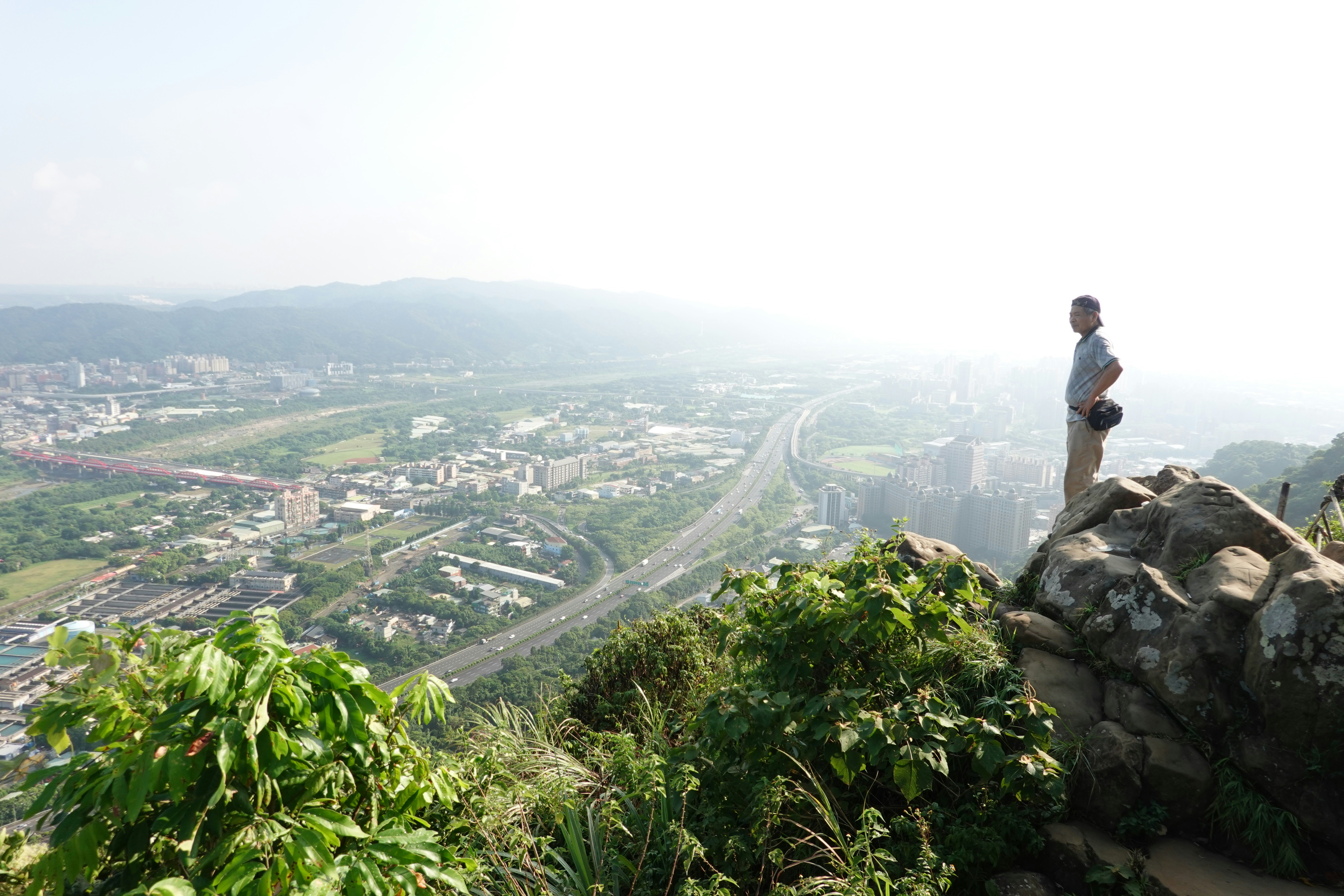 A man standing on top of a lush green hillside, 