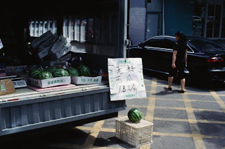 A person standing next to a truck filled with watermelons