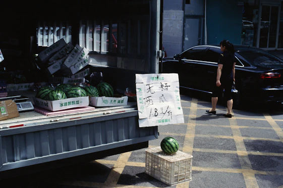 A person standing next to a truck filled with watermelons