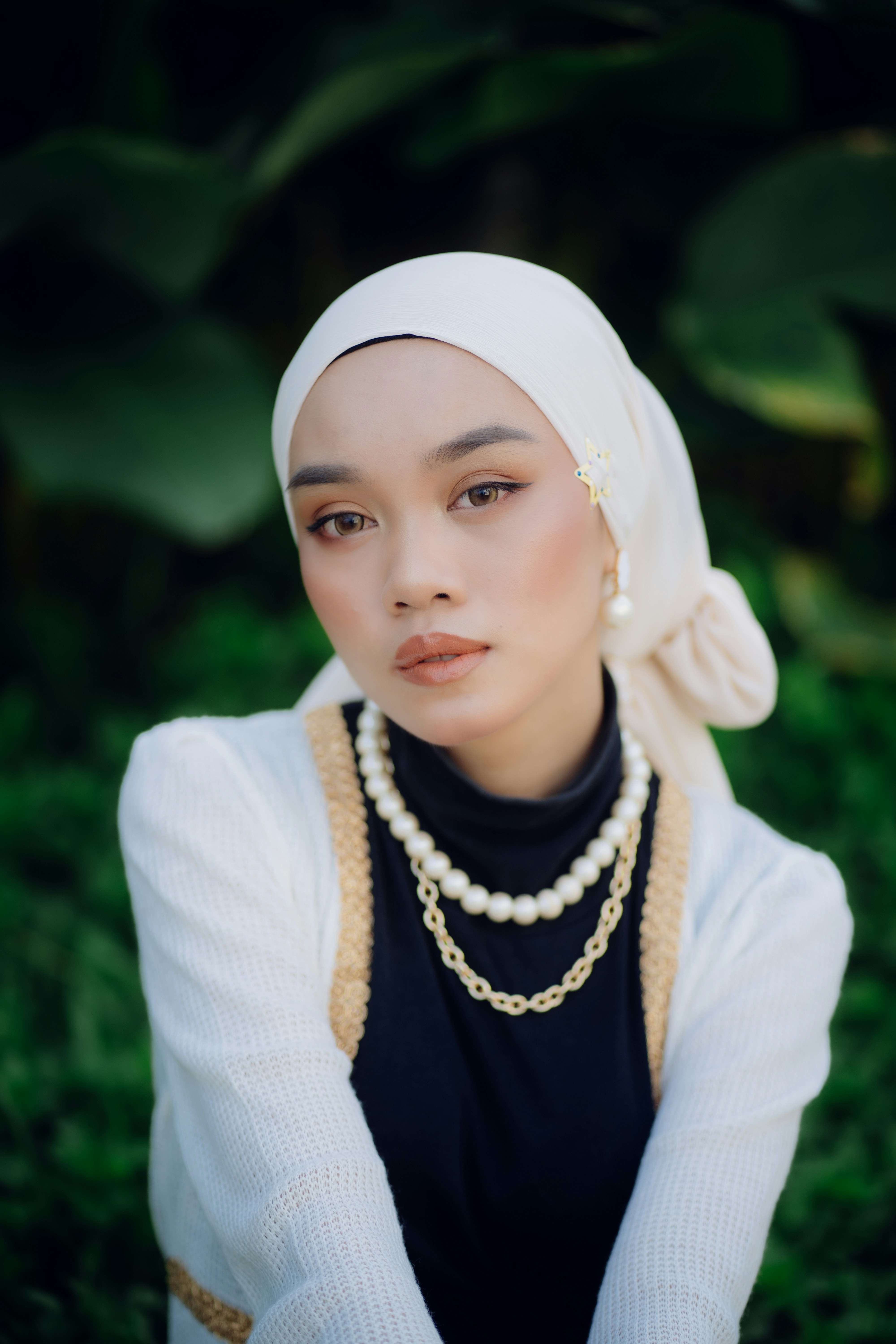 A woman wearing a white head scarf and pearls