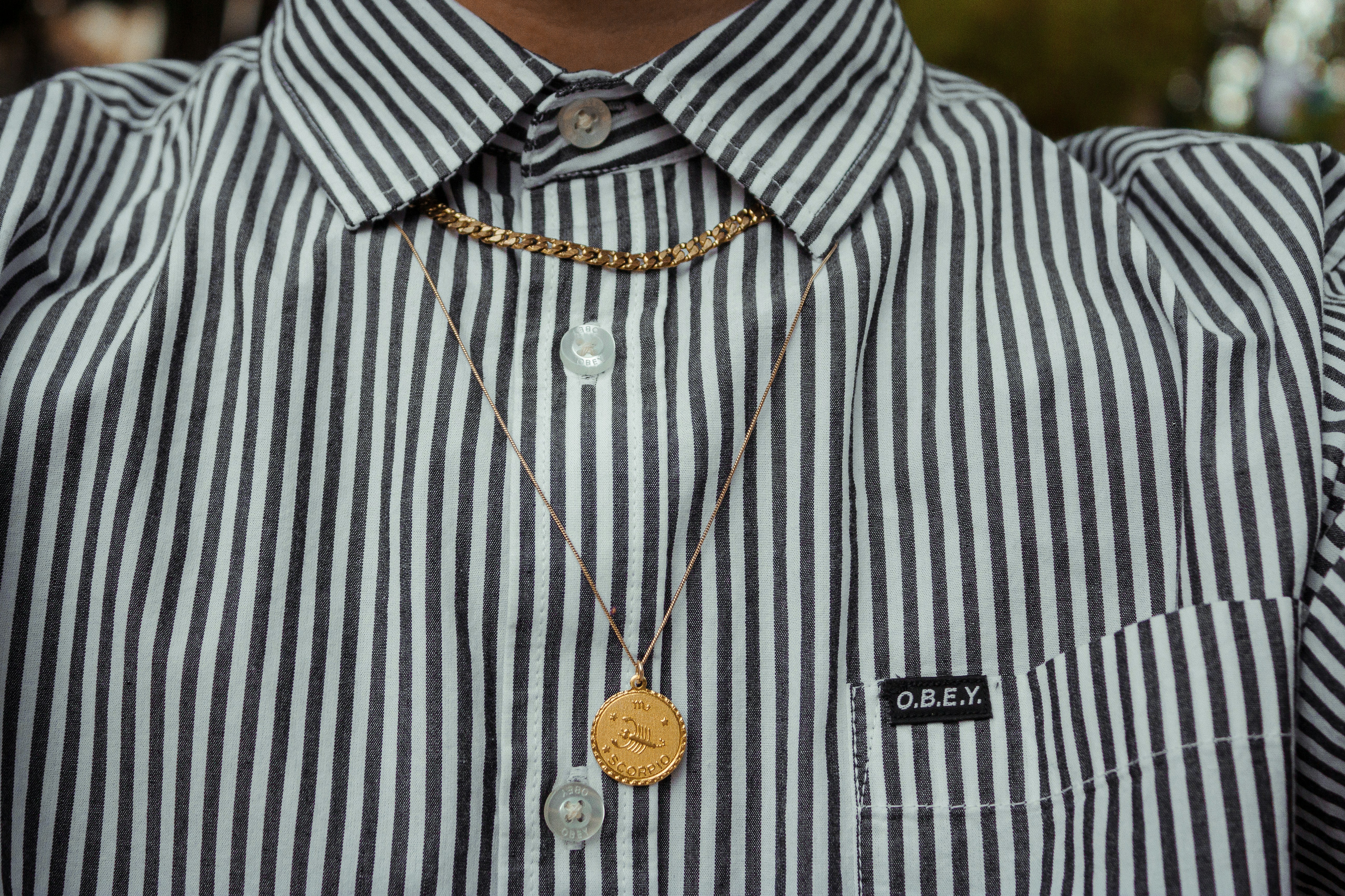 A man wearing a striped shirt and a gold necklace