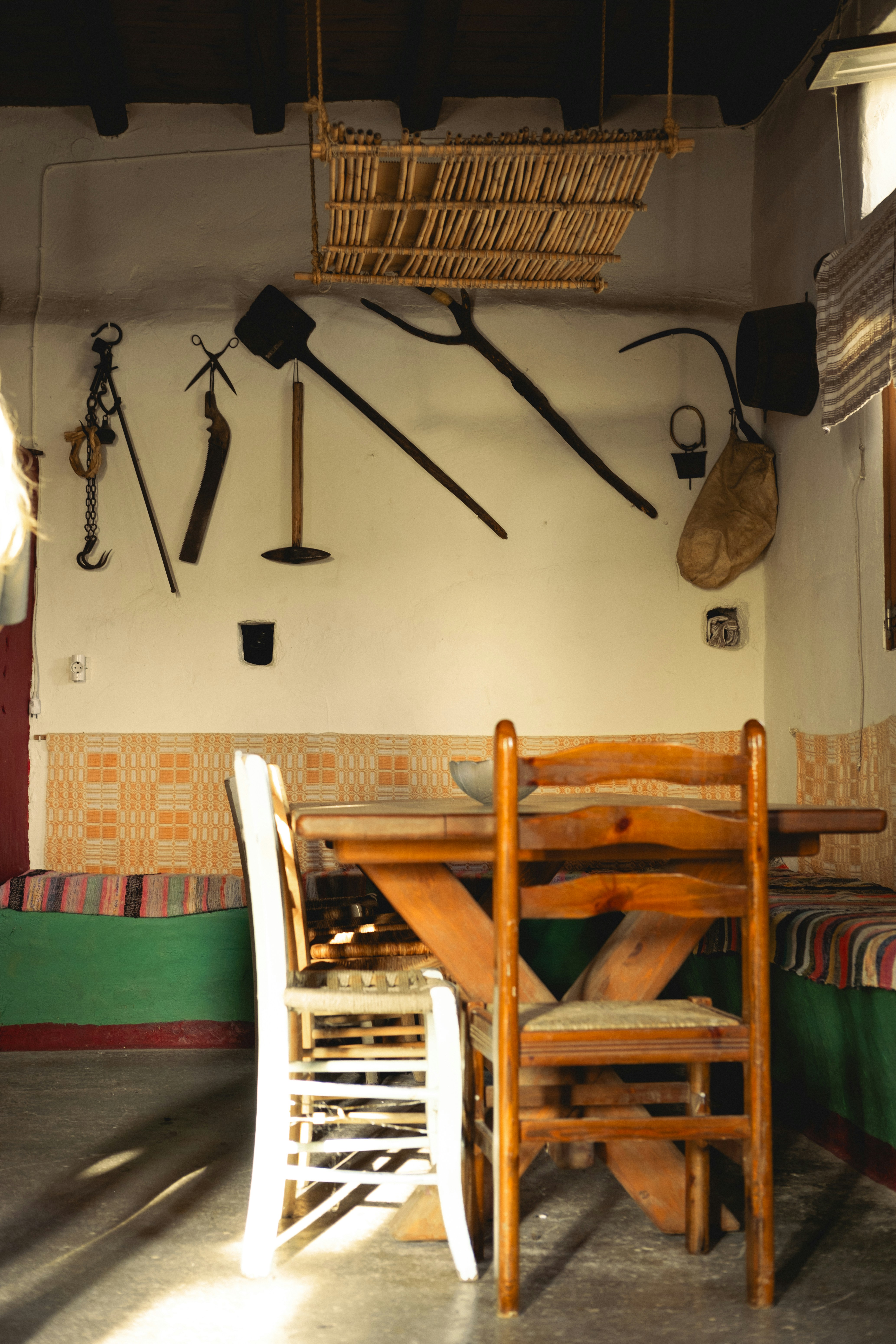 A table and chairs in a room with a wall of tools on the wall