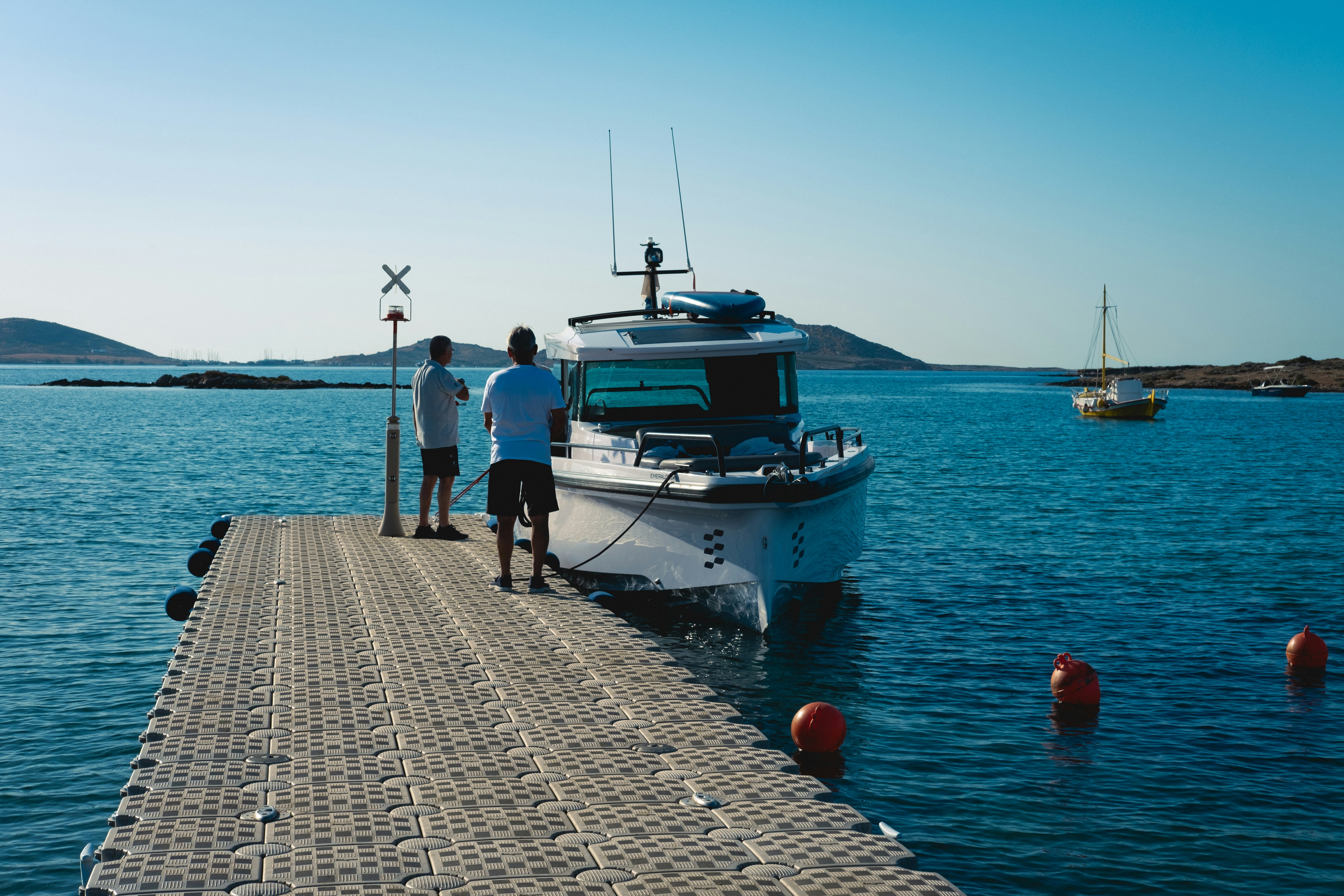 A couple of men standing on a dock next to a boat