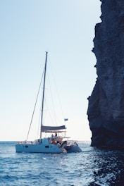 A sailboat in the water near a rocky cliff
