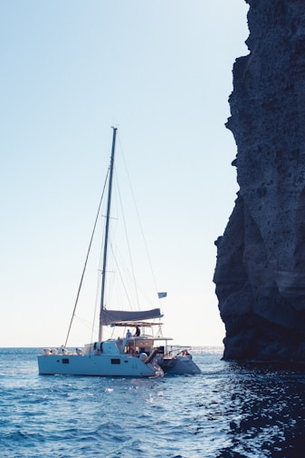 A sailboat in the water near a rocky cliff