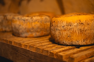 A group of cheeses sitting on a wooden shelf