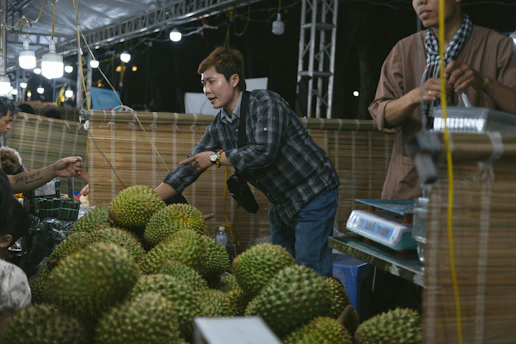 A group of men standing around a pile of fruit