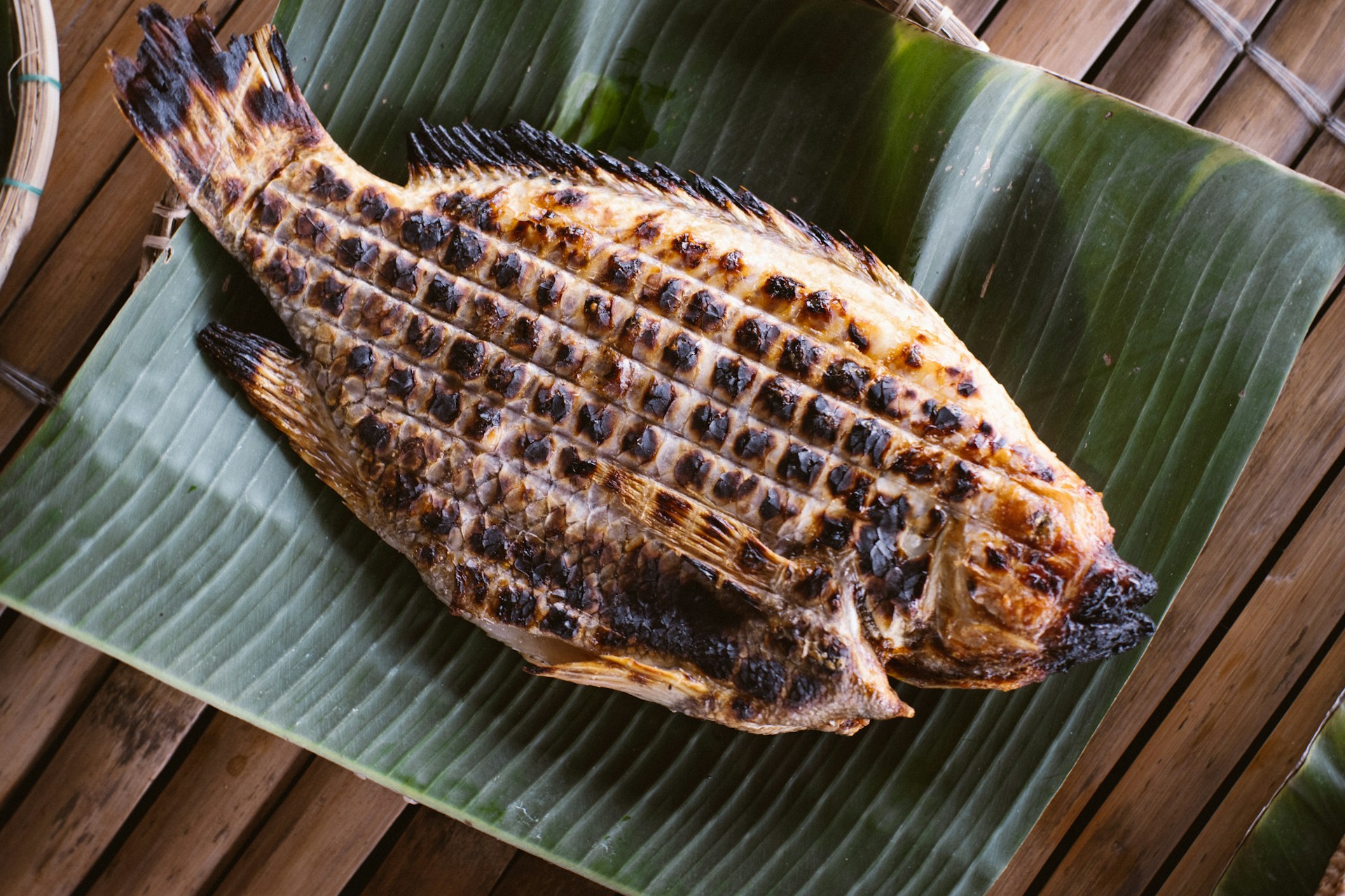 A grilled fish sitting on top of a banana leaf
