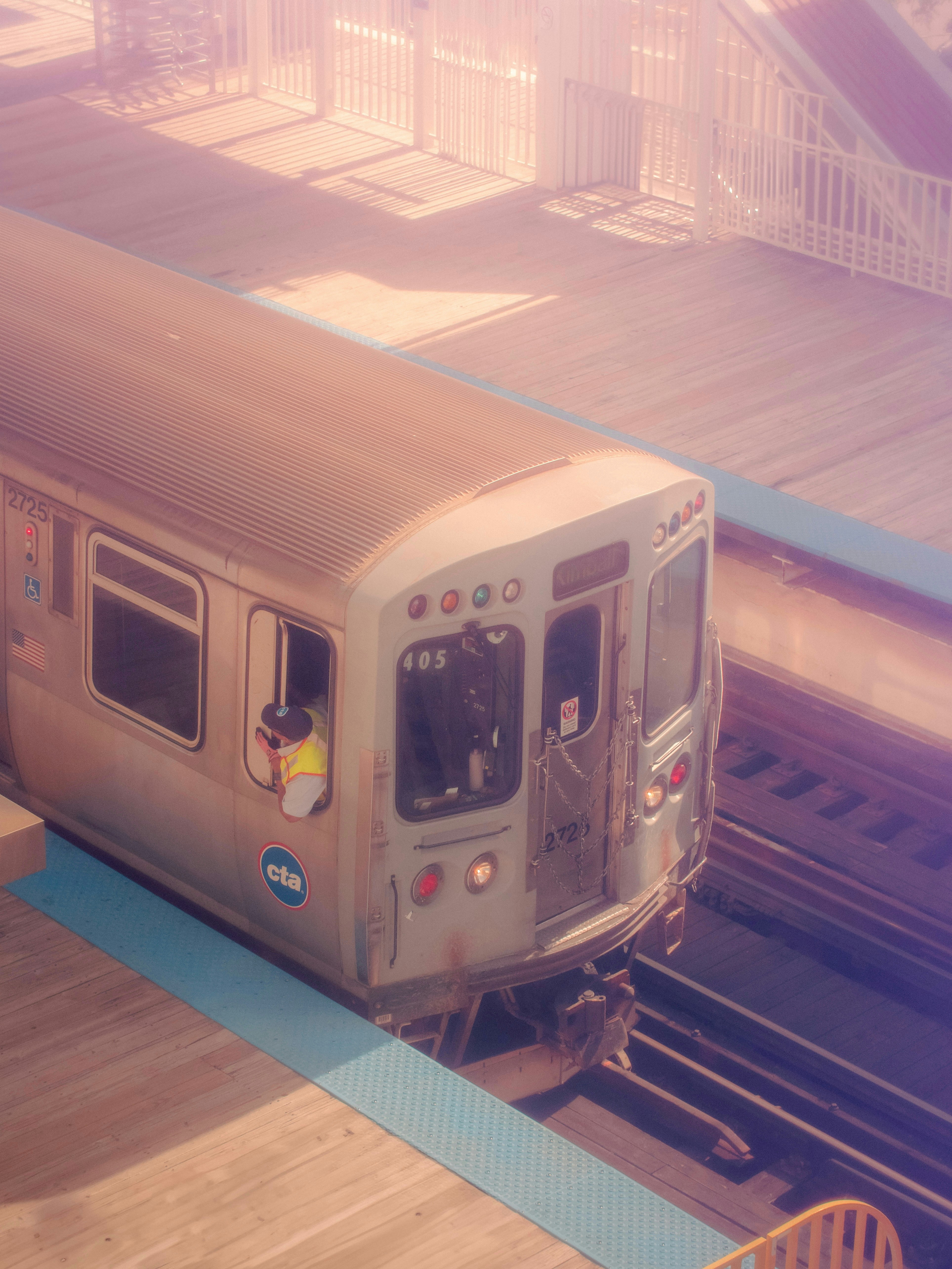 A silver train traveling down train tracks next to a platform