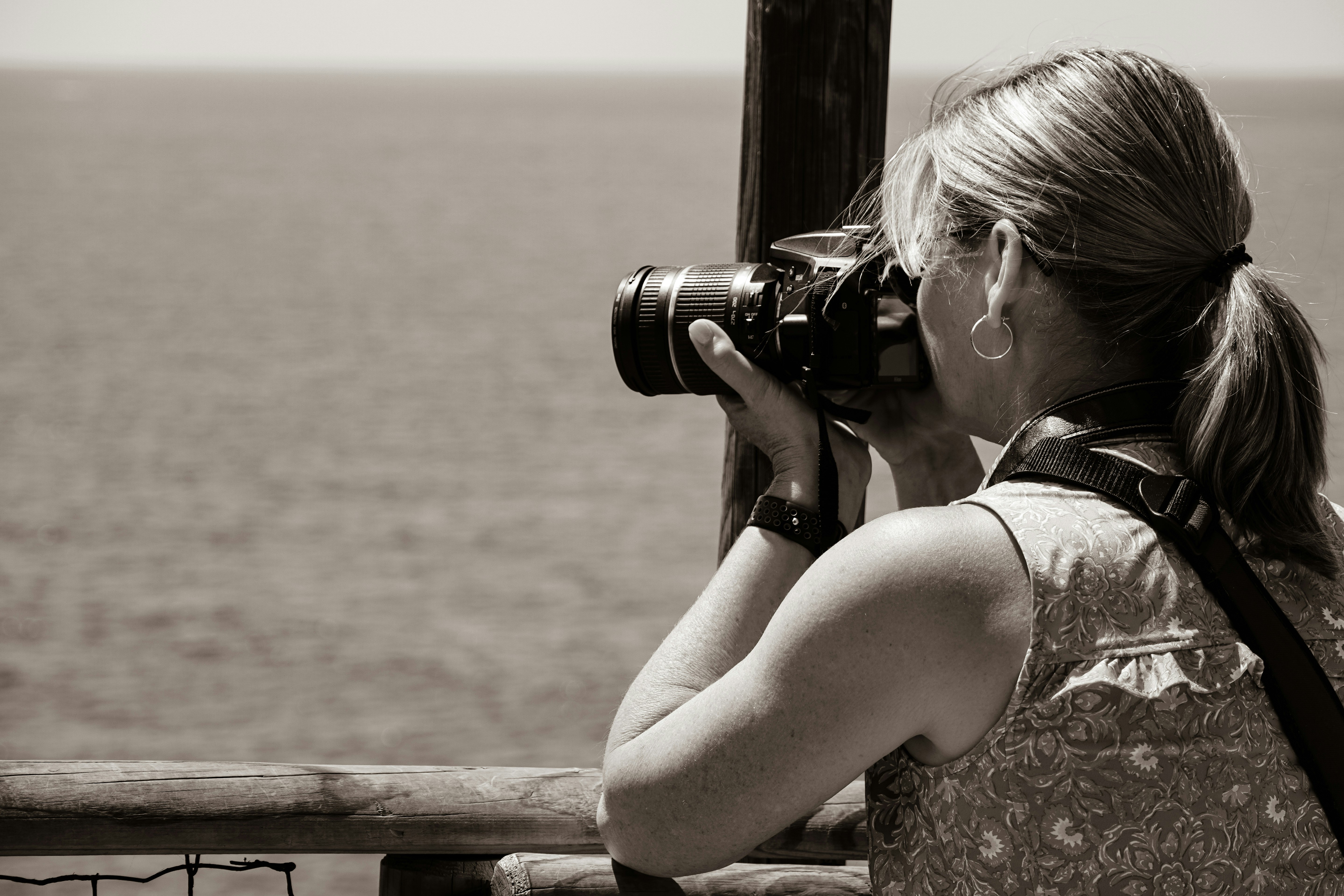 A woman taking a picture of the ocean with a camera