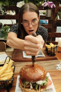 A woman is cutting a hamburger with a knife